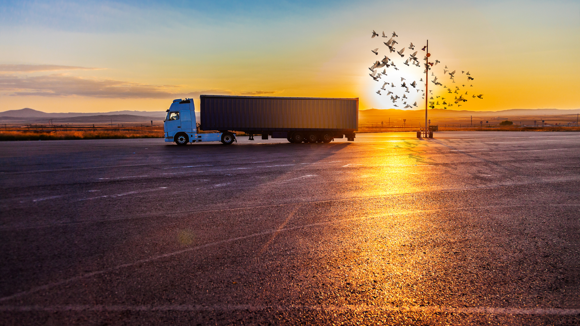 A lorry on a road against a sunset