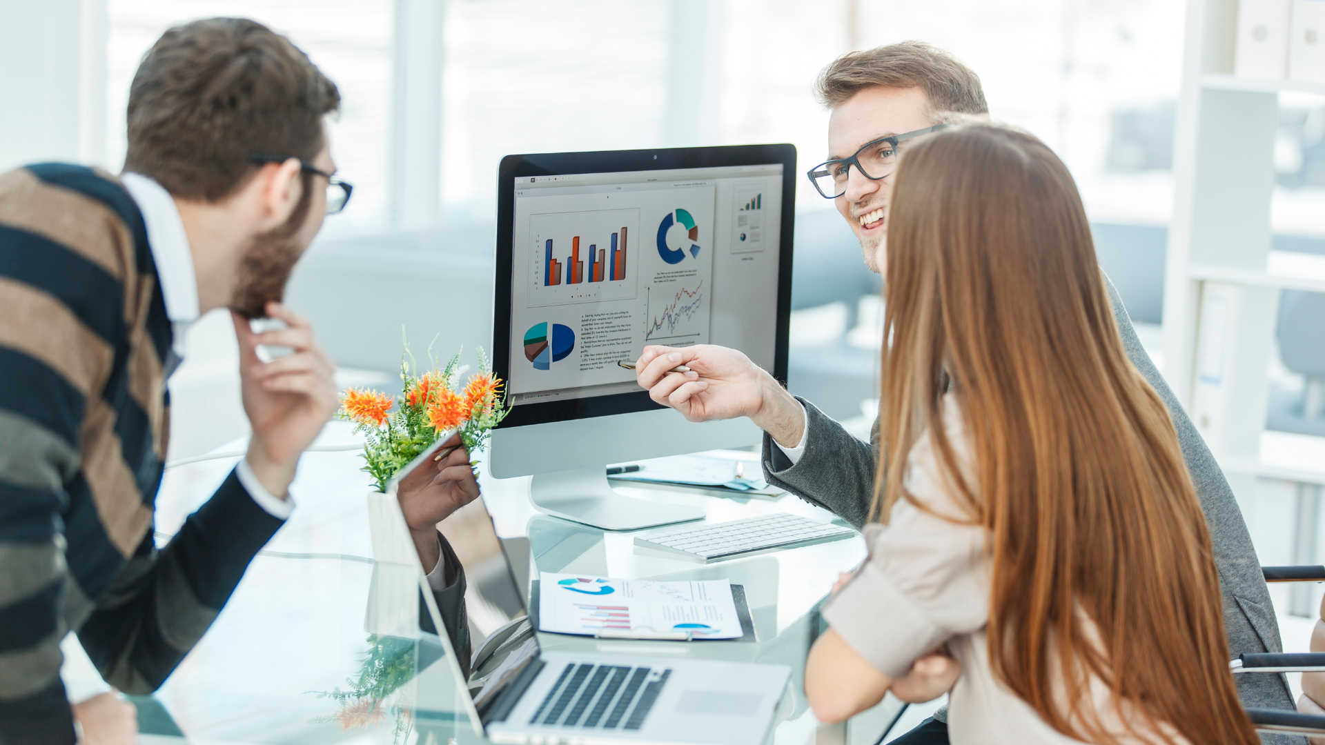 Three marketing professionals looking at charts and data