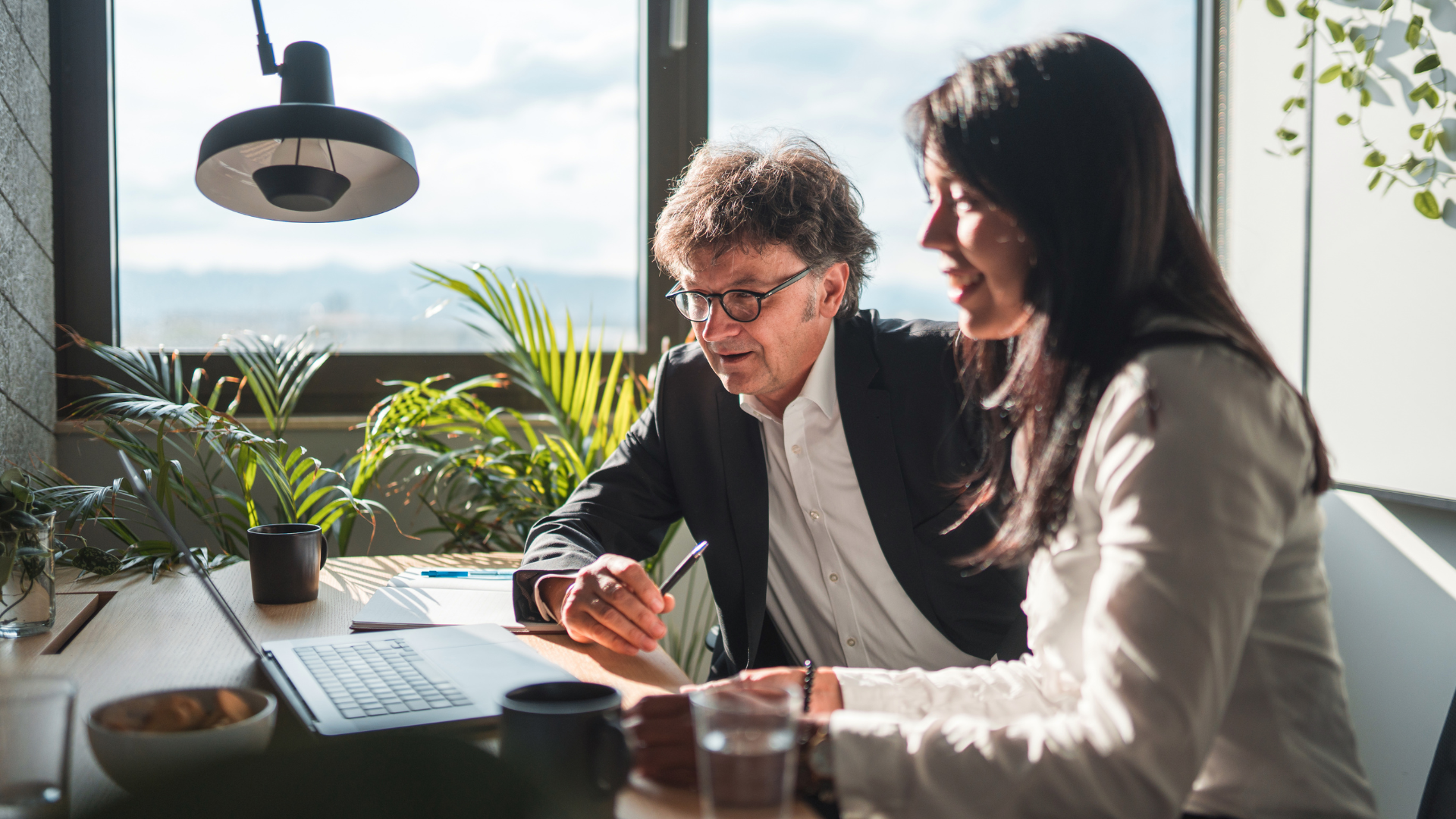 Two people in an office looking at a laptop