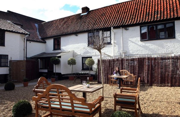 The beer garden of the White Hart Hotel, looking back at the hotel, with a bench, two chairs, and a table in the foreground
