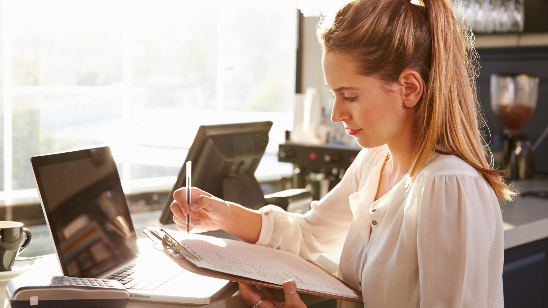 A woman with a form on a notepad, managing a restaurant