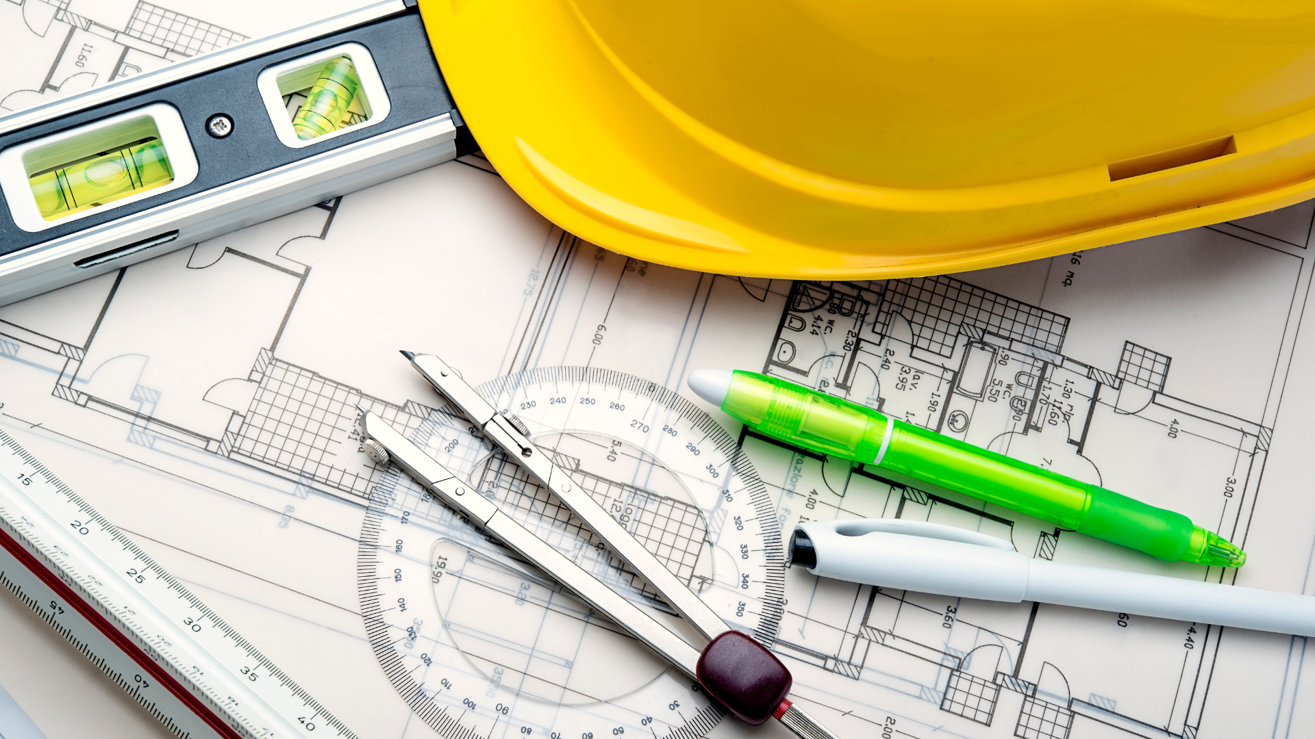 A hard hat and measuring tools on top of construction drawings