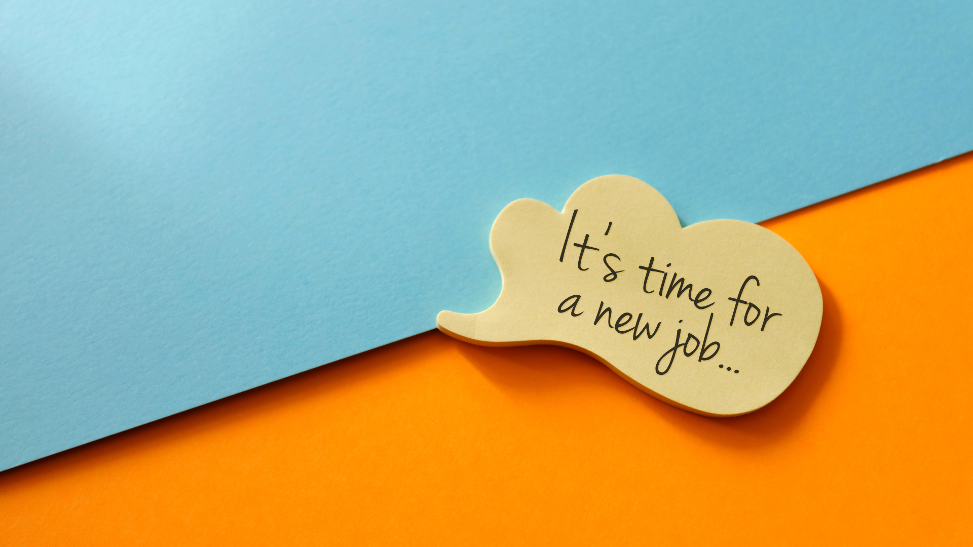 A wooden cutout of a cloud with the words "it's time for a new job" on it, resting between an orange and blue background