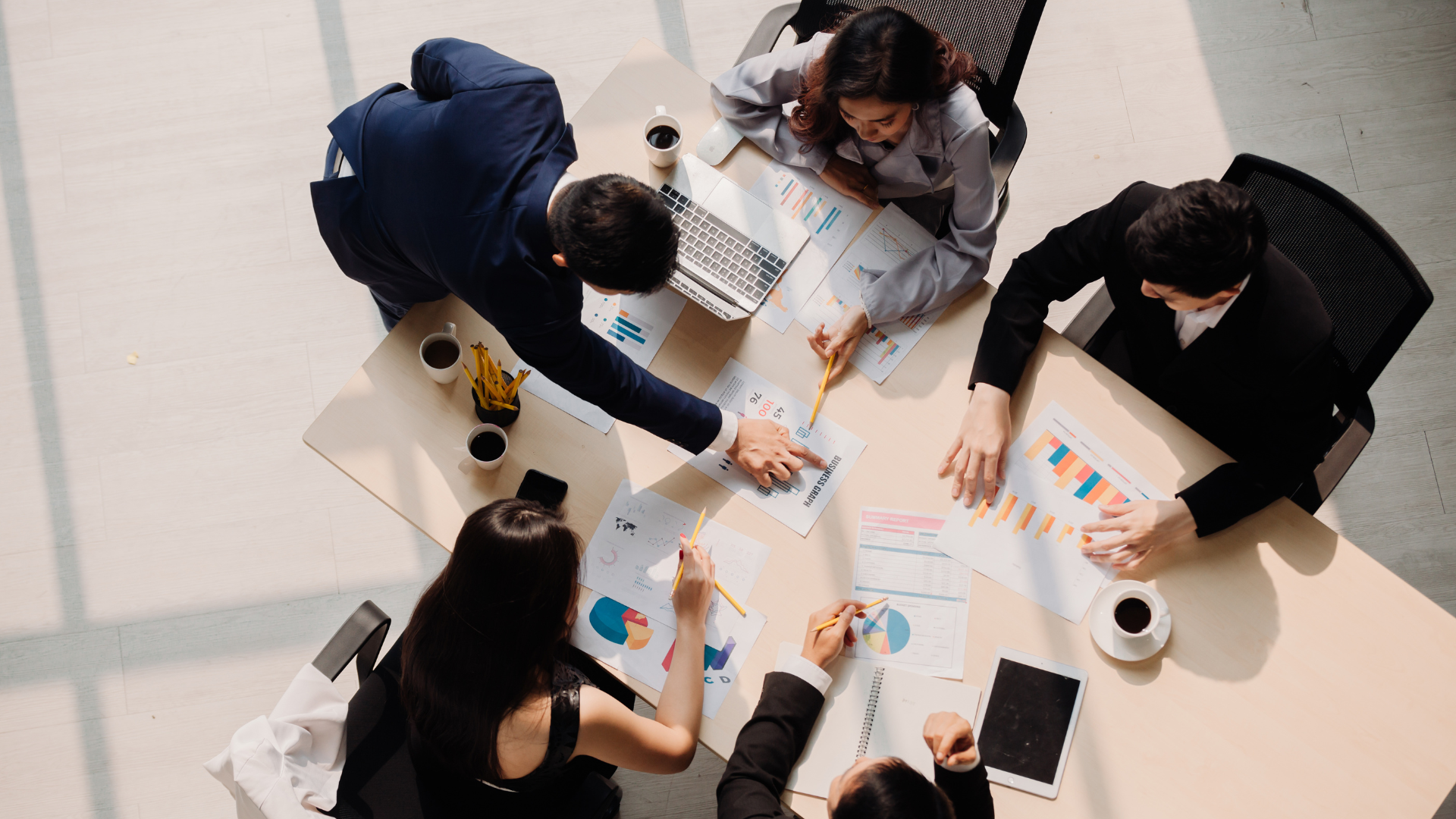 Five people sat round a table discussing finance reports