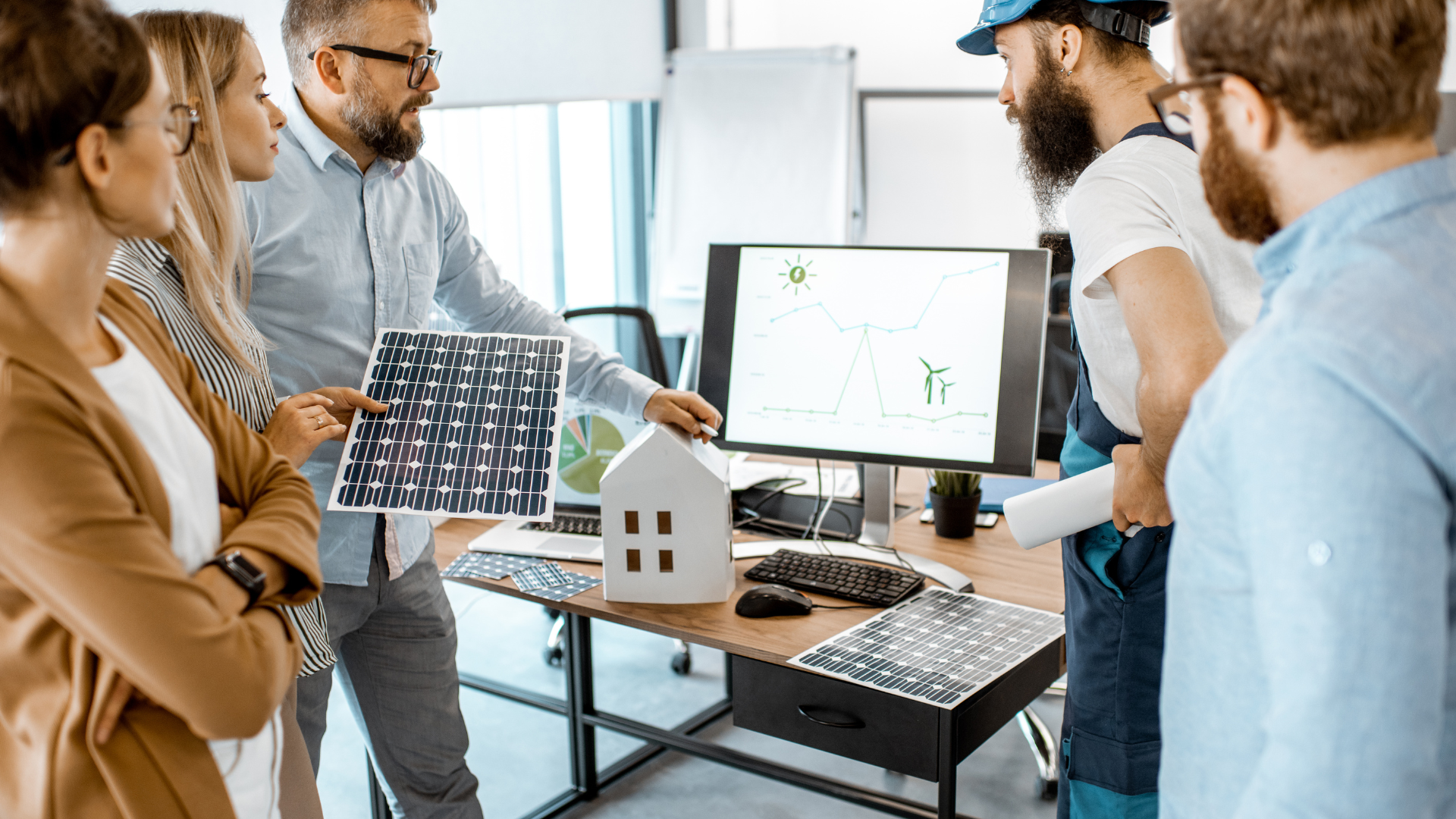 A group of people looking at a diagram on a computer. The diagram shows the benefits of investing in green technologies