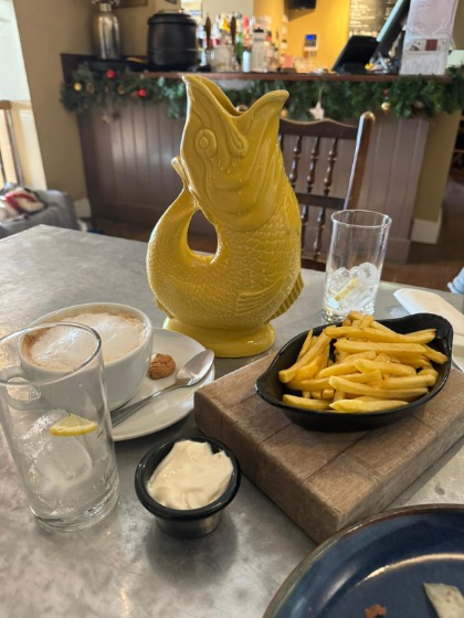 a plate of chips, a bowl of sauce, a mug of coffee, and two glasses of water on a dining table