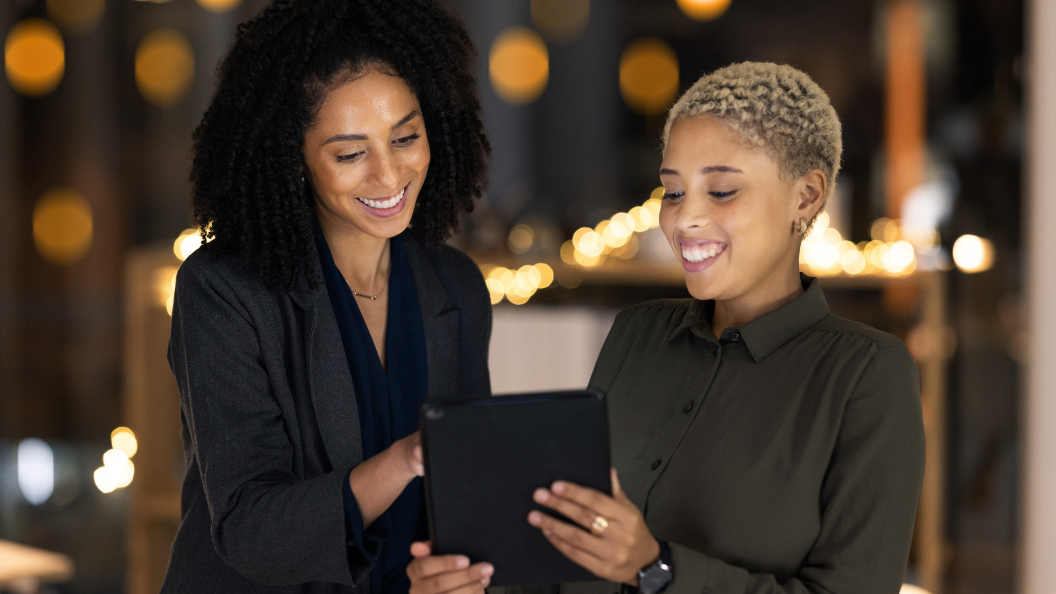 An image of two workers looking at a digital tablet together