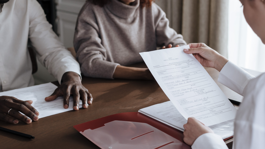 An image of a person reading over an employment contract. There are two other people sat across the table from them