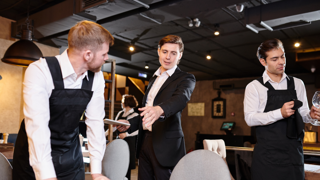 An image of a manager instructing staff on table setup in a fancy restaurant