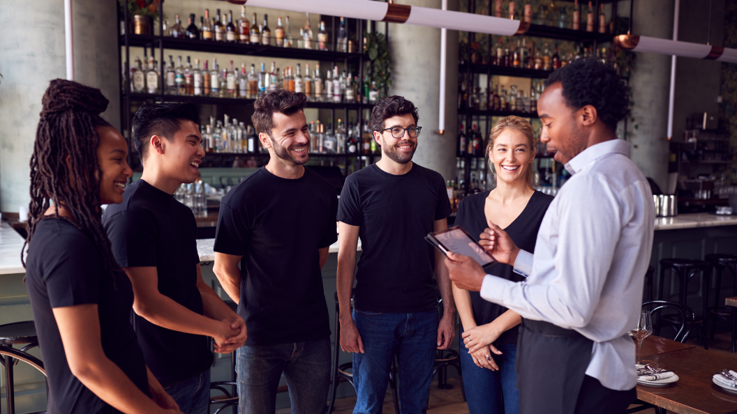 An image of a Front of House Manager speaking to front of house staff in a restaurant