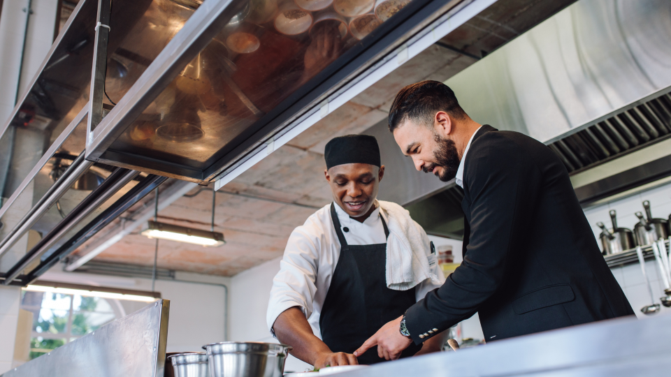 An image of a restaurant manager discussing dishes with his head-chef