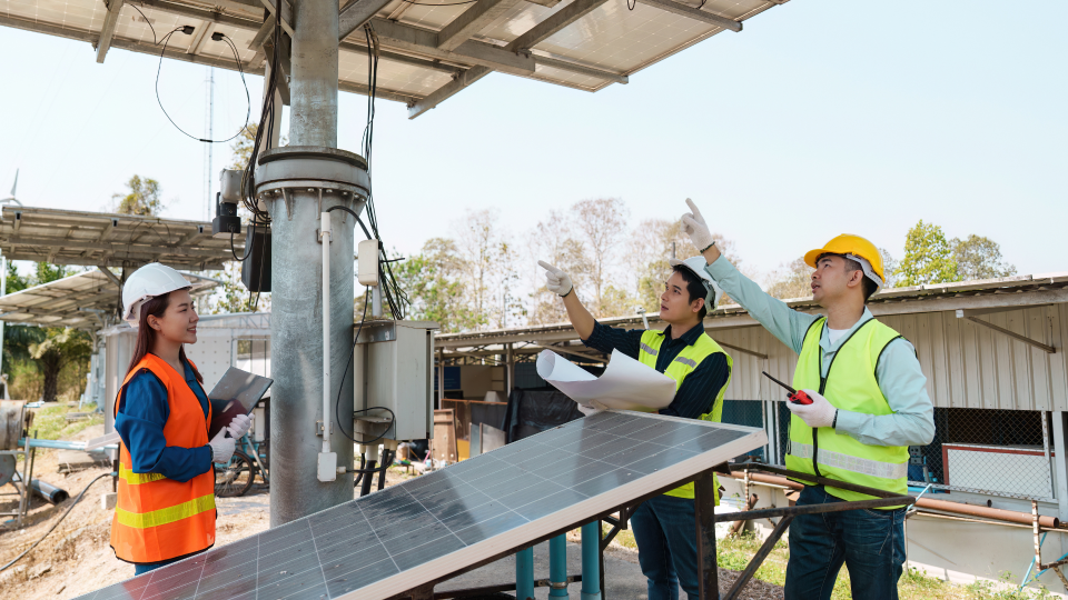 An image of 3 construction workers discussing solar panel installations on a construction site.
