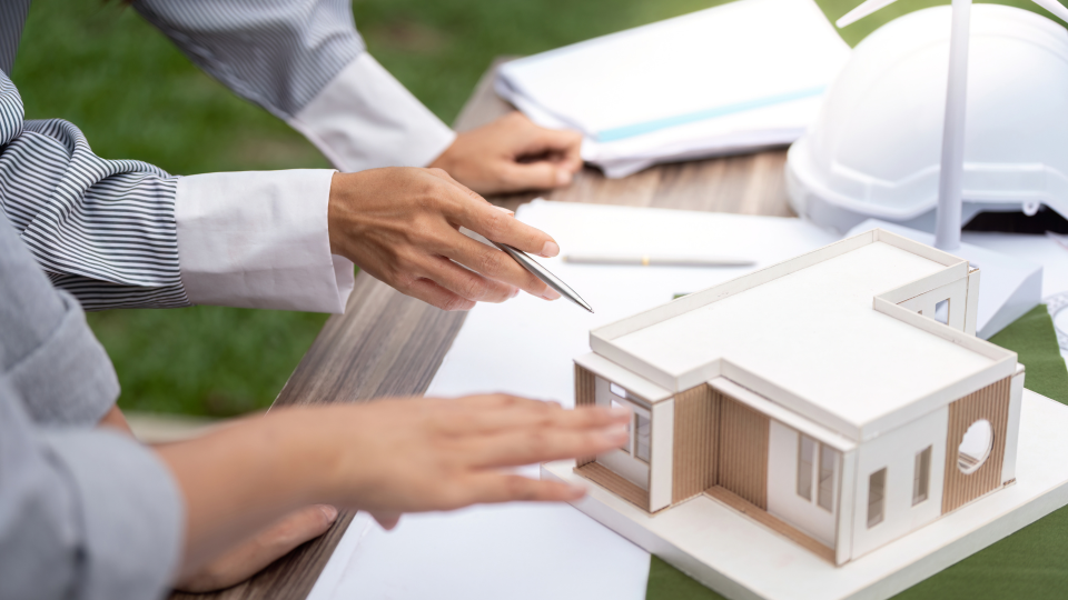 A close up image of two people discussing a physical 3D model of a modern sustainable home.