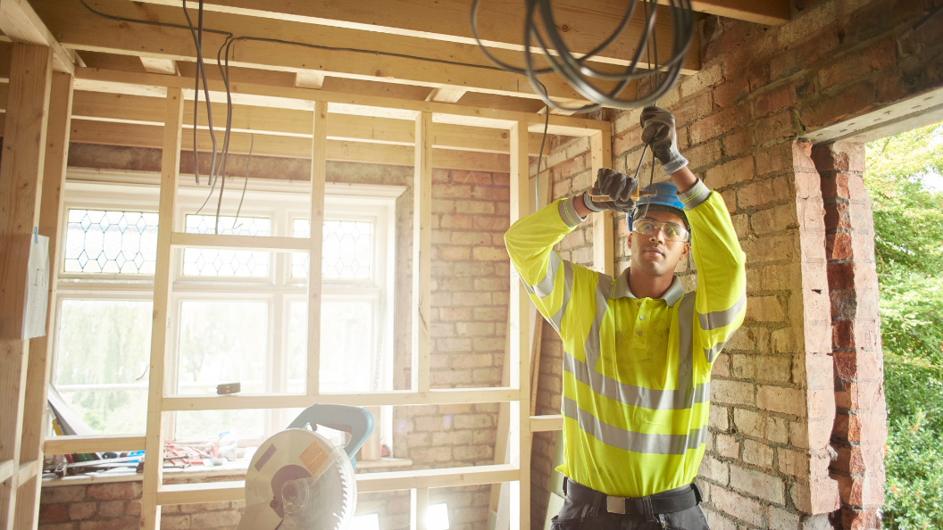 An image of an electrician working on wiring inside a new home