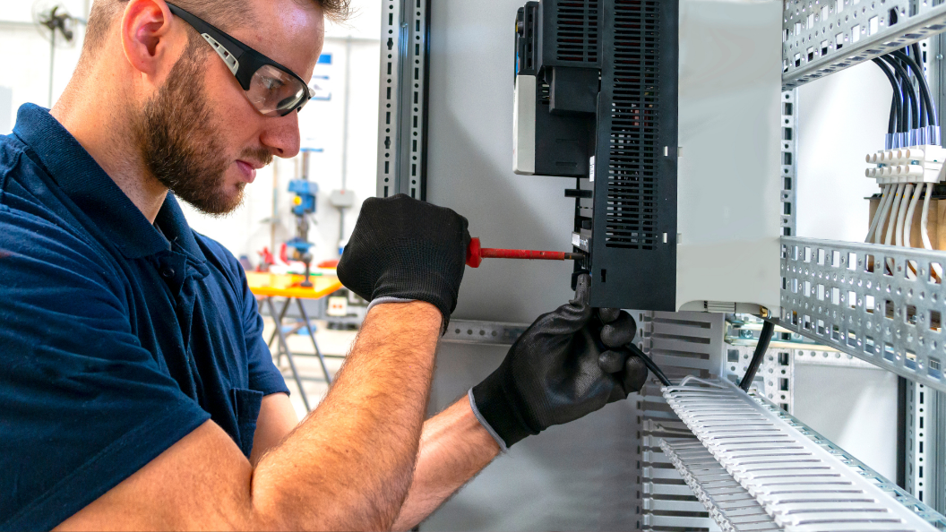An image of an electrician working on a circuit board in a factory
