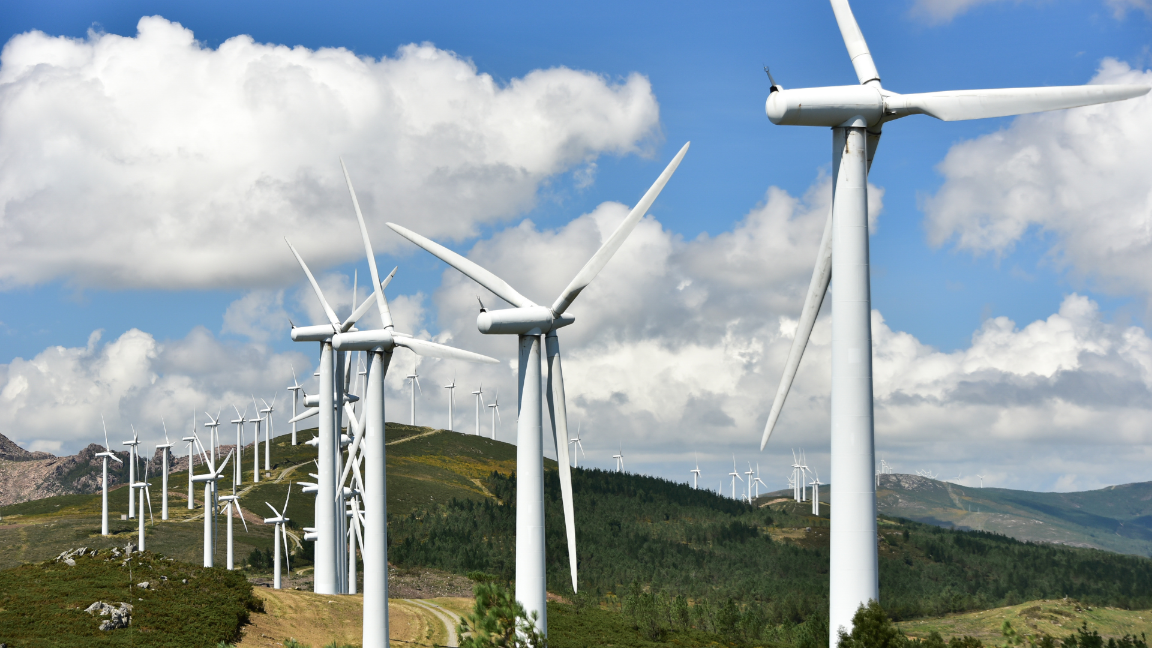 An image of a wind farm running along the top of a grassy mountain ridge