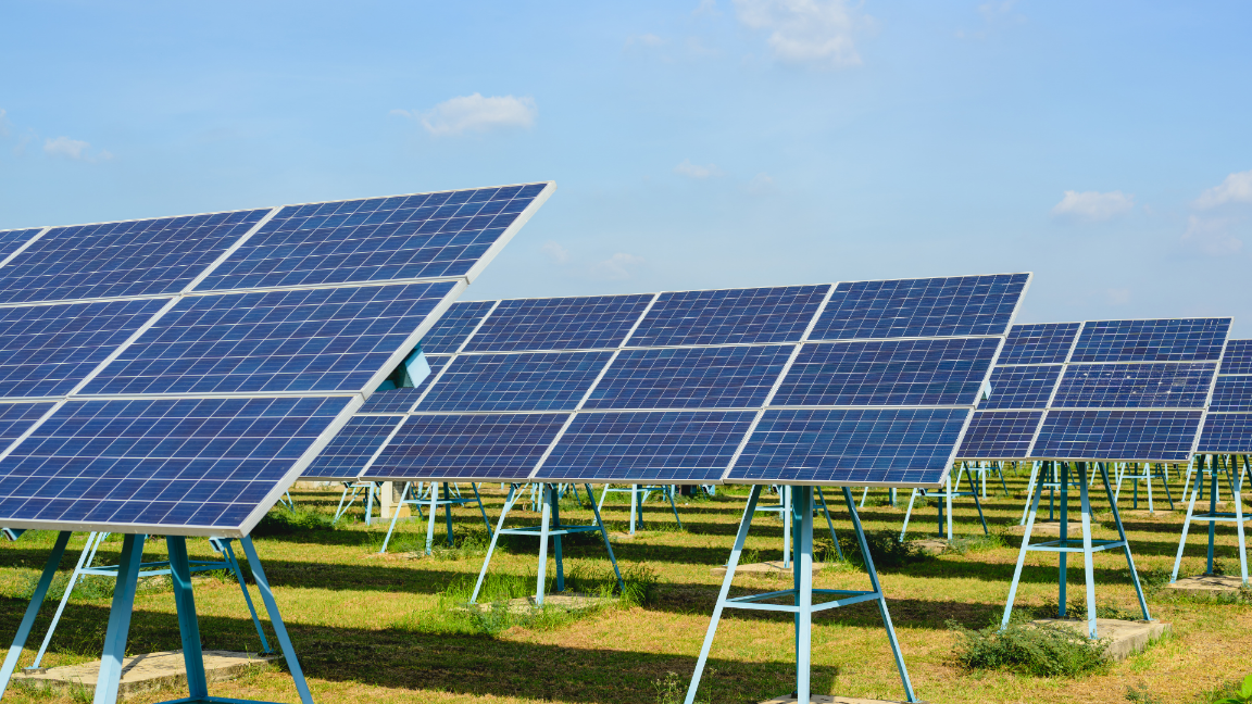 An image of solar panels in a grassy field against a blue sky