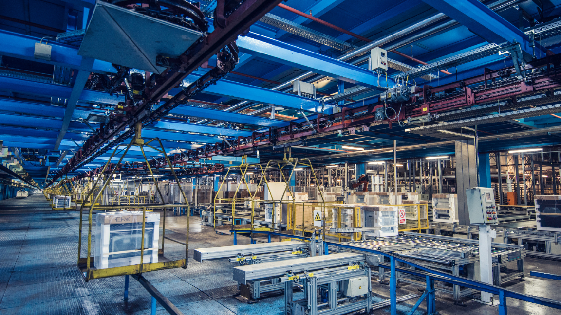 The inside of a large factory, with production lines and materials around the room