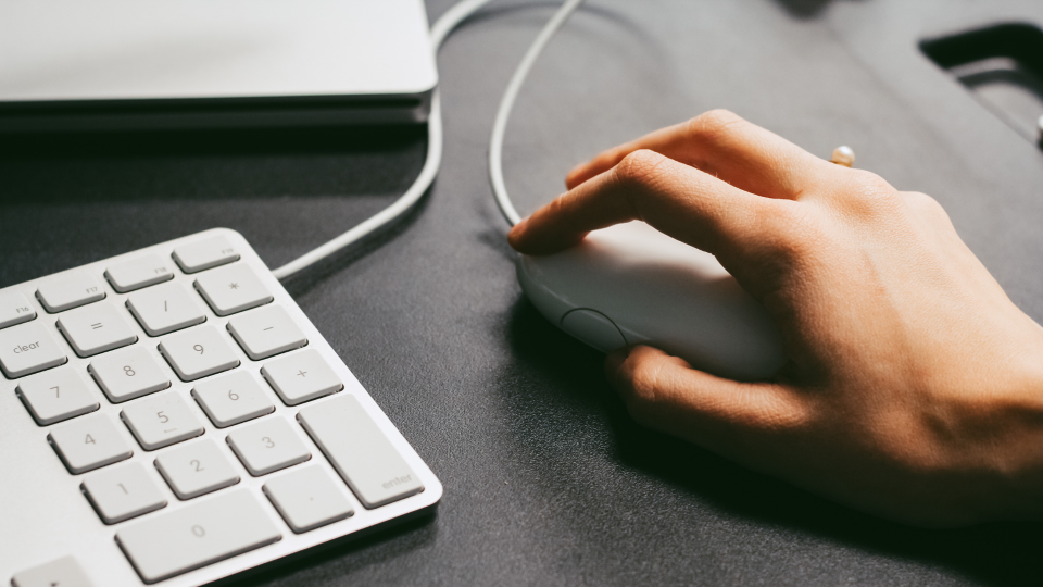 A close-up image of a person using a mouse for a mac computer