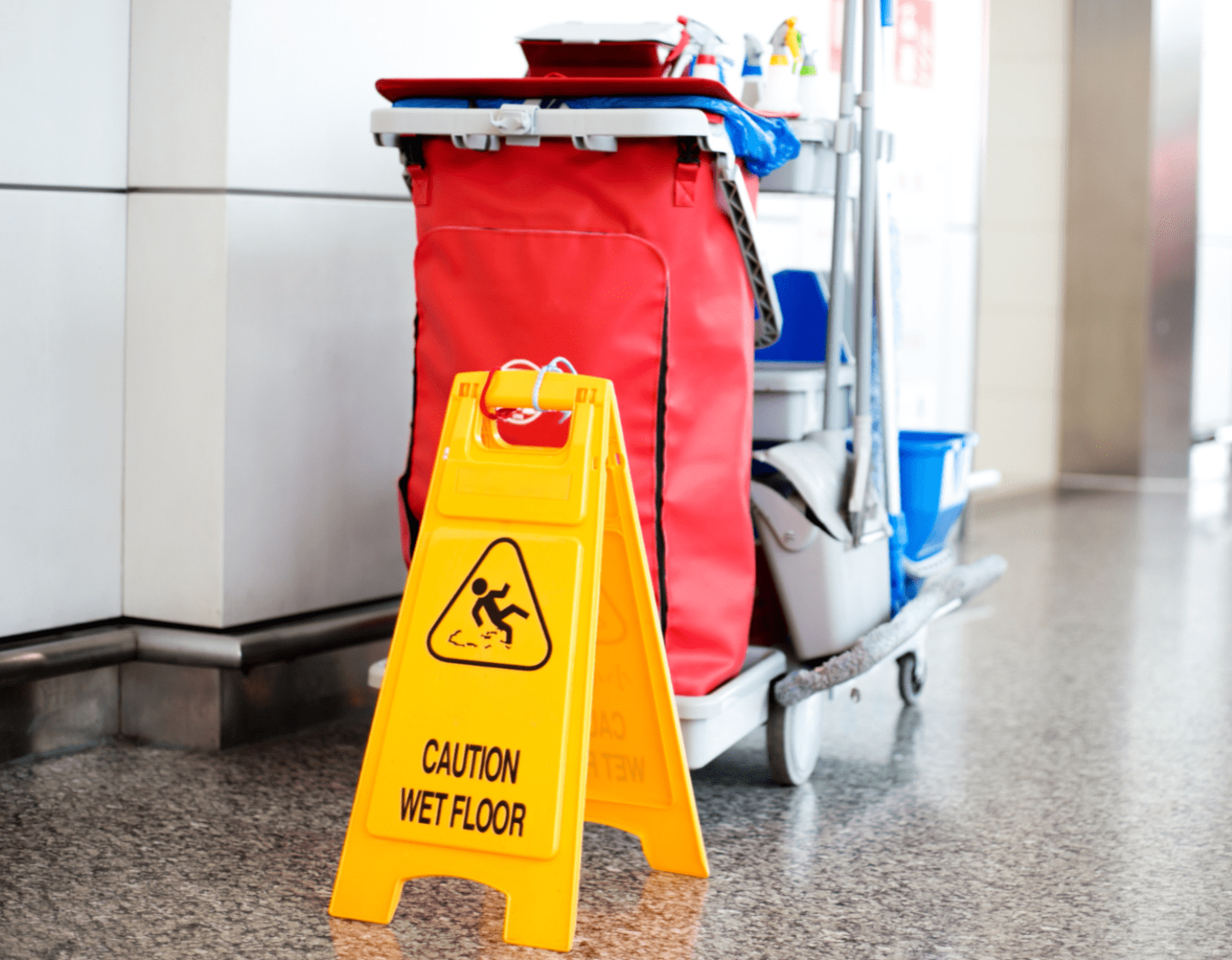 A cleaning cart with a wet-floor sign next to it
