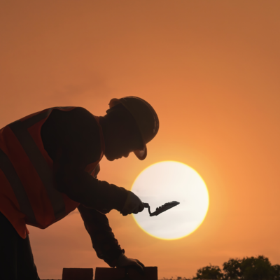 A man working on a construction site against a sunset