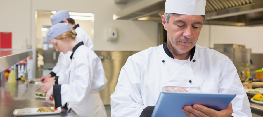 Chefs at a workstation with a tablet