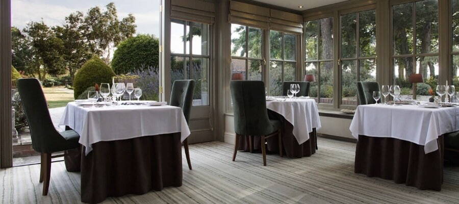 An image of one Morston Hall's dining rooms. There is an open door showing the grounds around the property.