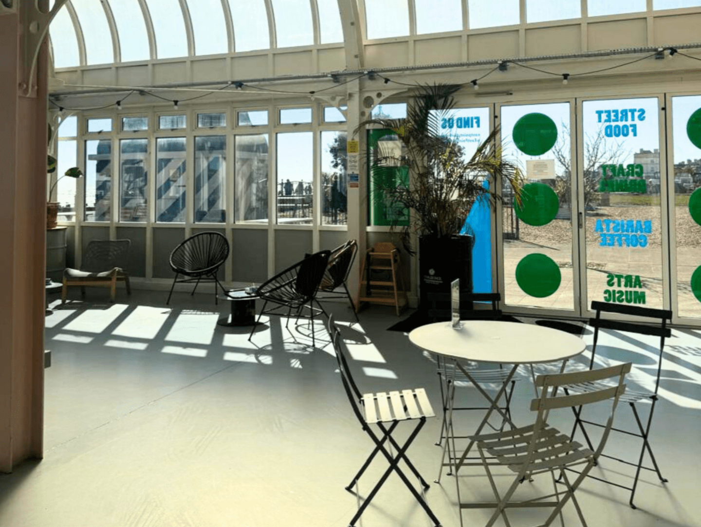 An image of the interior of the East Point Pavilion. There is a table and chairs near a glass window, looking out to a grass field.