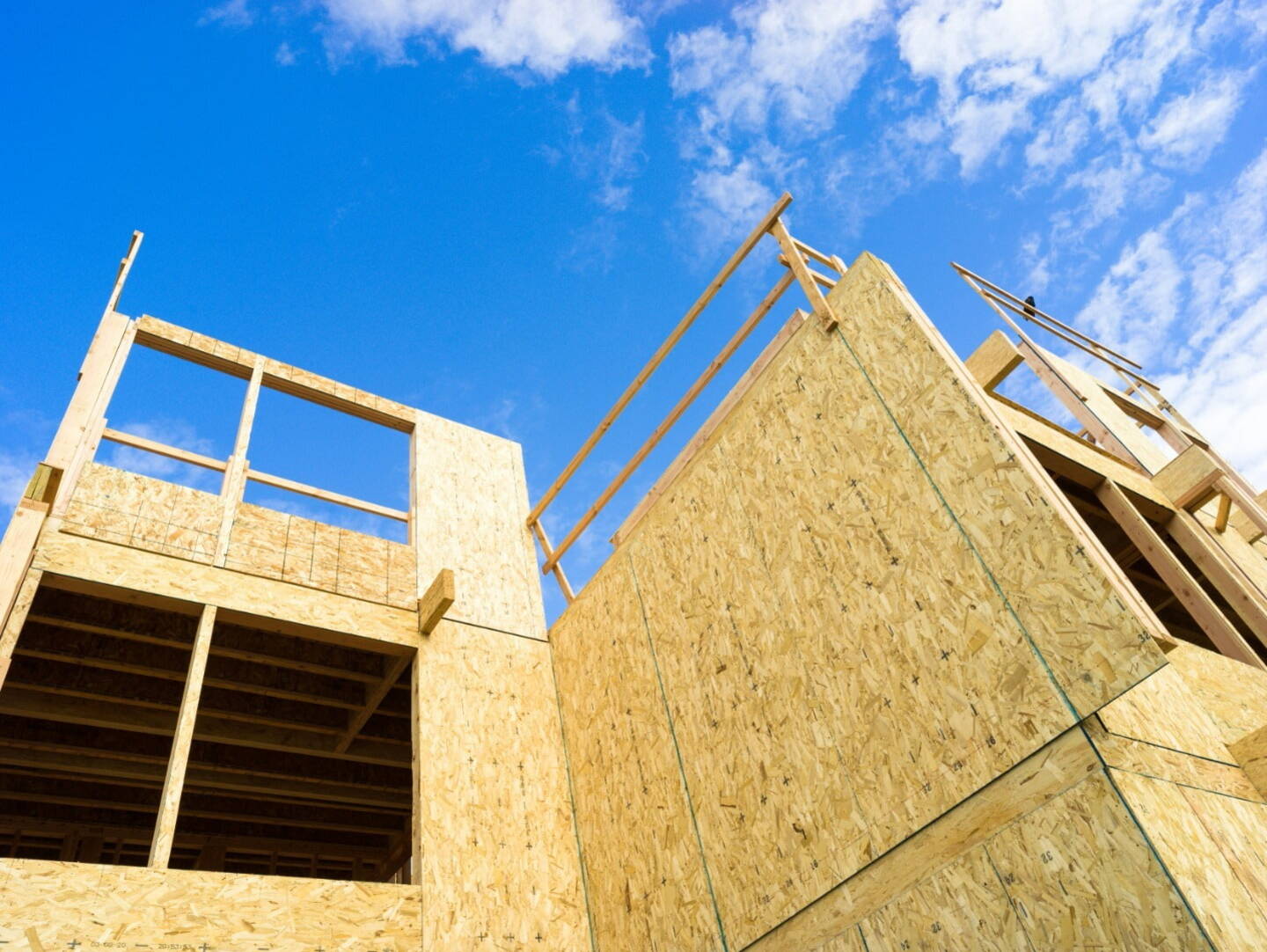 A large pre-fabricated wooden structure outside against a blue sky with clouds