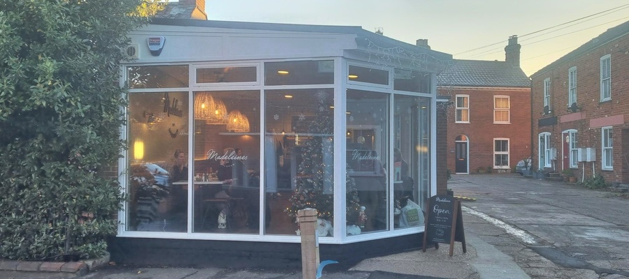 An exterior shot of Madeleines, showing the glass windows and white wooden framework
