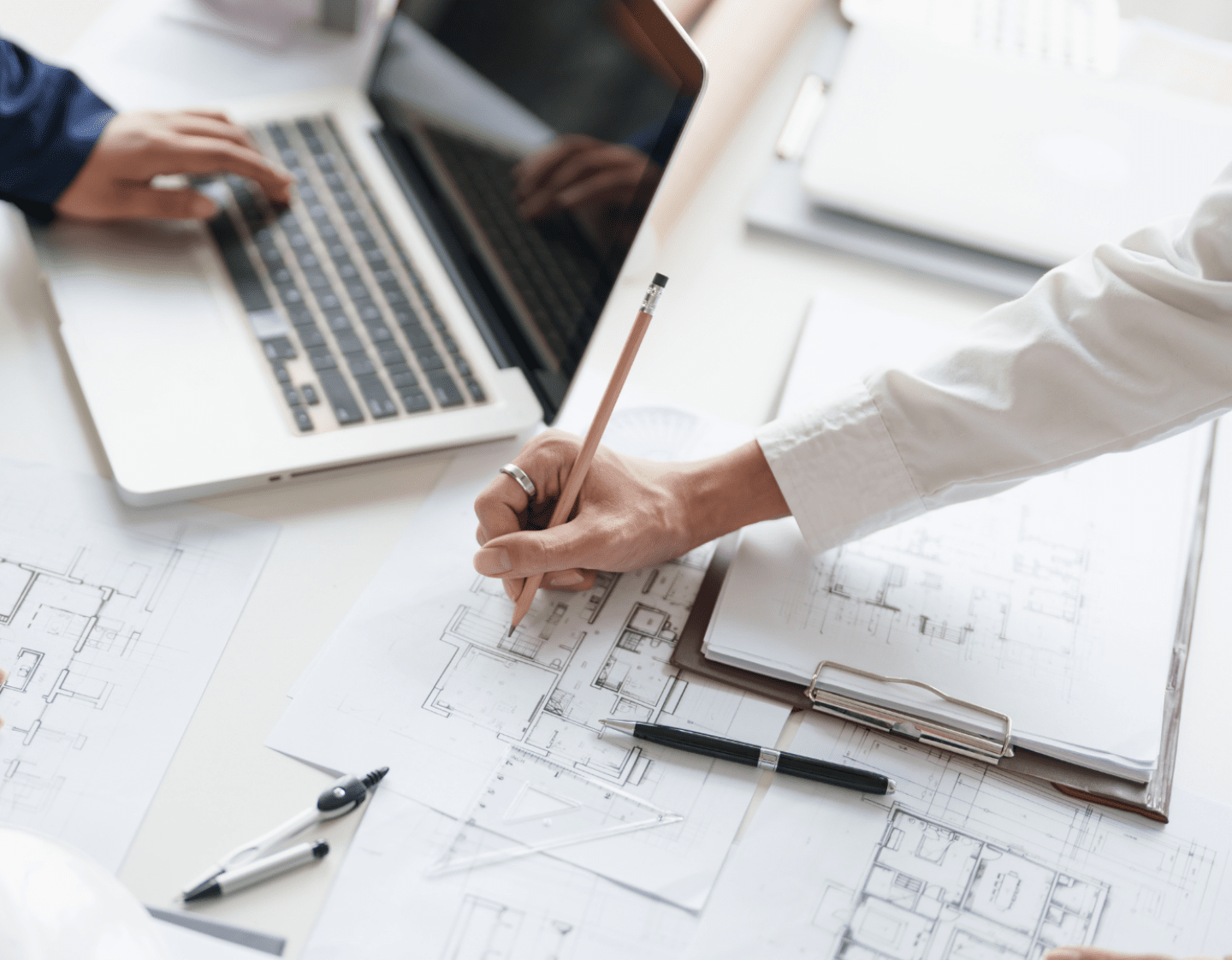 An image of two people working on construction drawings and costings