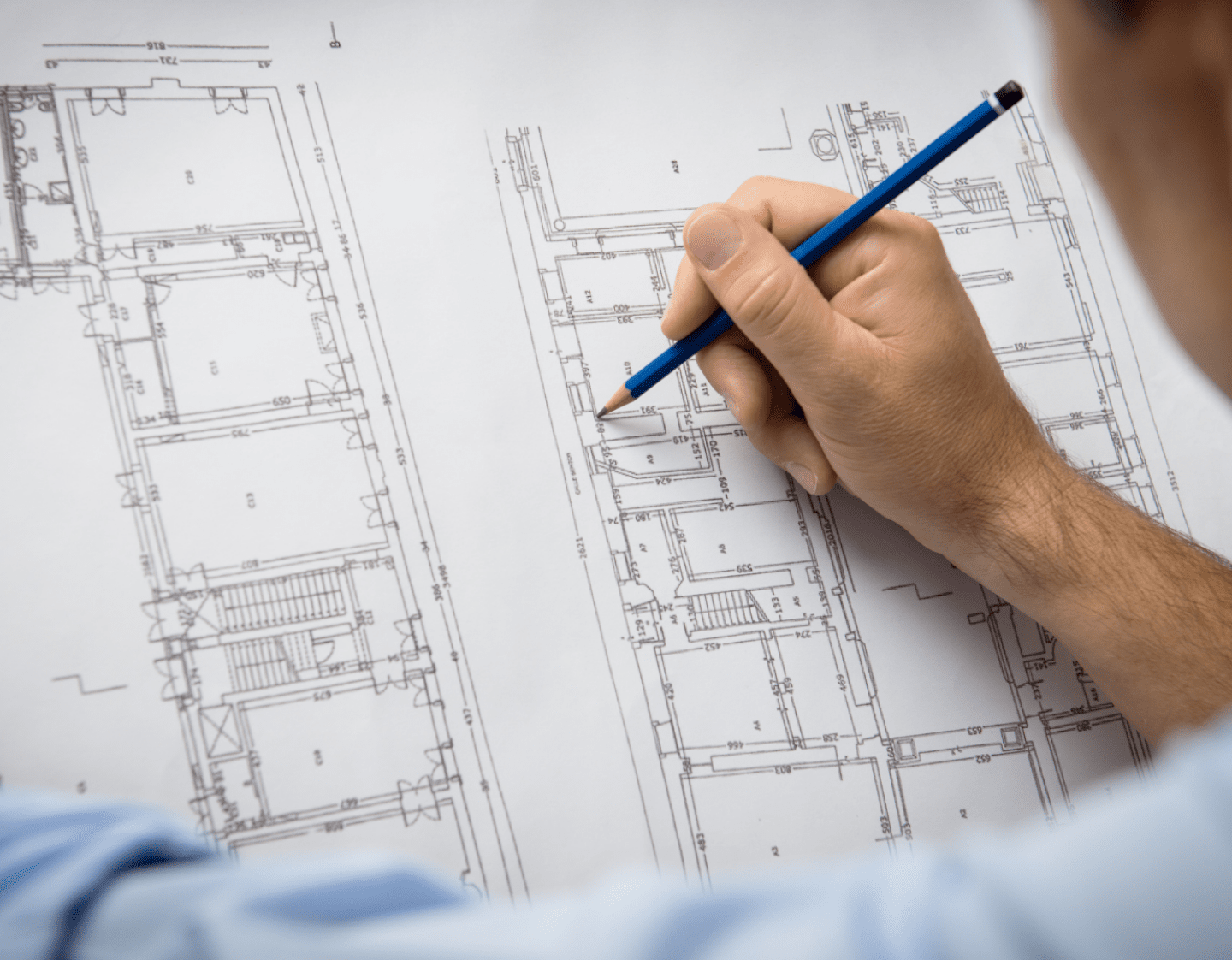 A man working on an architectural drawing with a pencil